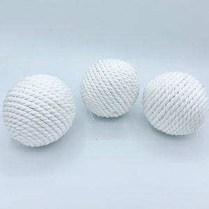 Puede incluir: Tres bolas de cuerda blancas, cada una con una textura y un patr&oacute;n diferentes. Las bolas est&aacute;n hechas de cuerda natural y son perfectas para agregar un toque de estilo n&aacute;utico a cualquier habitaci&oacute;n.