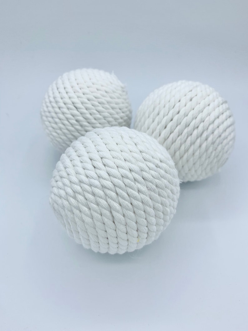 Puede incluir: Tres bolas de cuerda blancas, cada una hecha de cuerda blanca tejida apretadamente, est&aacute;n dispuestas sobre una superficie blanca.