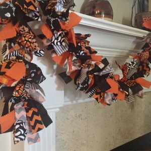 May include: A Halloween-themed garland made of fabric strips in orange, black, and white patterns. The garland features various designs, including chevron, skeletons, and pumpkin motifs, creating a festive and decorative accent for the holiday season.