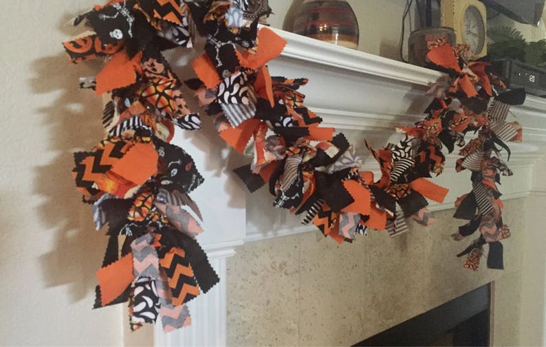 May include: A Halloween-themed garland made of fabric strips in orange, black, and white patterns. The garland features various designs, including chevron, skeletons, and pumpkin motifs, creating a festive and decorative accent for the holiday season.