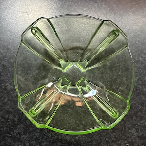 May include: A translucent light green glass bowl featuring a square-shaped rim with rounded corners and four distinct, raised radiating ribs that extend from the centre towards each corner, creating a symmetrical, segmented interior design.