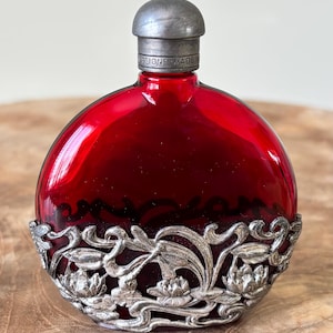 Frasco de perfume Vintage First Impressions (Terri Gill) de peltre inglés con diseño repujado y vidrio rojo rubí, reactivo a los rayos UV, cadmio.