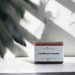 May include: A brown bar of soap with the text "SIMPLE Traditions Caribbean Coconut fresh. handcrafted. luxury. SOAP 4.5 OZ" printed on the label.