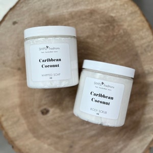 May include: Two white jars with black labels. The labels read "SIMPLE Traditions" and "Caribbean Coconut". One jar is labeled "WHIPPED SOAP" and the other is labeled "BODY SCRUB".