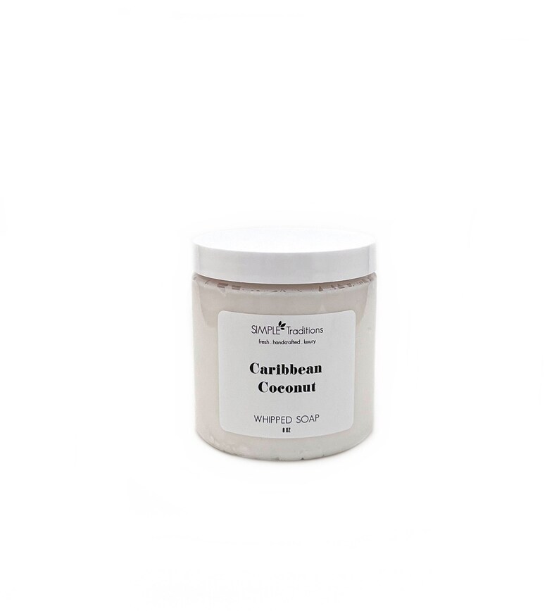 May include: A cylindrical container of light pink whipped soap with a white lid. The label reads Simple Traditions, fresh. handcrafted. luxury, Caribbean Coconut, WHIPPED SOAP, and 8 OZ. The container is opaque and has a smooth, matte finish.