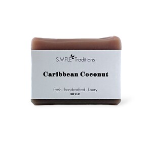 May include: A bar of brown soap with a white label that reads "SIMPLE Traditions Caribbean Coconut fresh. handcrafted. luxury SOAP 4.5 OZ"