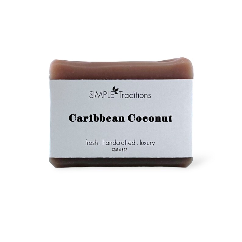 May include: A bar of brown soap with a white label that reads "SIMPLE Traditions Caribbean Coconut fresh. handcrafted. luxury SOAP 4.5 OZ"