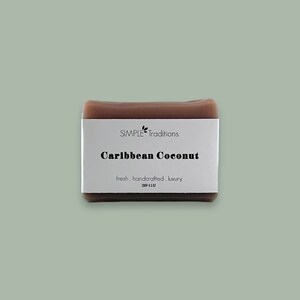 May include: A brown bar of soap with a white label that reads "SIMPLE Traditions Caribbean Coconut fresh. handcrafted. luxury SOAP 4.5 OZ".