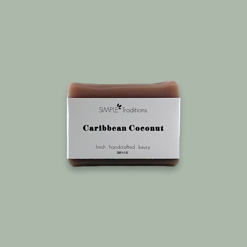 May include: A brown bar of soap with a white label that reads "SIMPLE Traditions Caribbean Coconut fresh. handcrafted. luxury SOAP 4.5 OZ".
