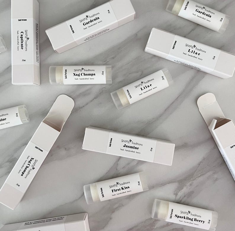 May include: A variety of lip balm tubes with different scents, including Gardenia, Jasmine, Lilac, Nag Champa, Captivate, First Kiss, and Sparkling Berry. The lip balms are packaged in white boxes with black text.