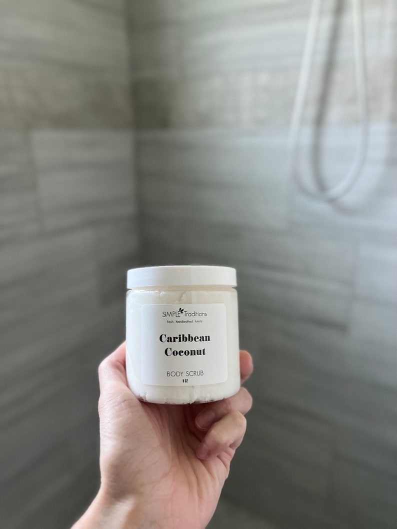 May include: A white jar of body scrub with a black label that reads "SIMPLE Traditions fresh handcrafted luxury Caribbean Coconut BODY SCRUB 4 oz."