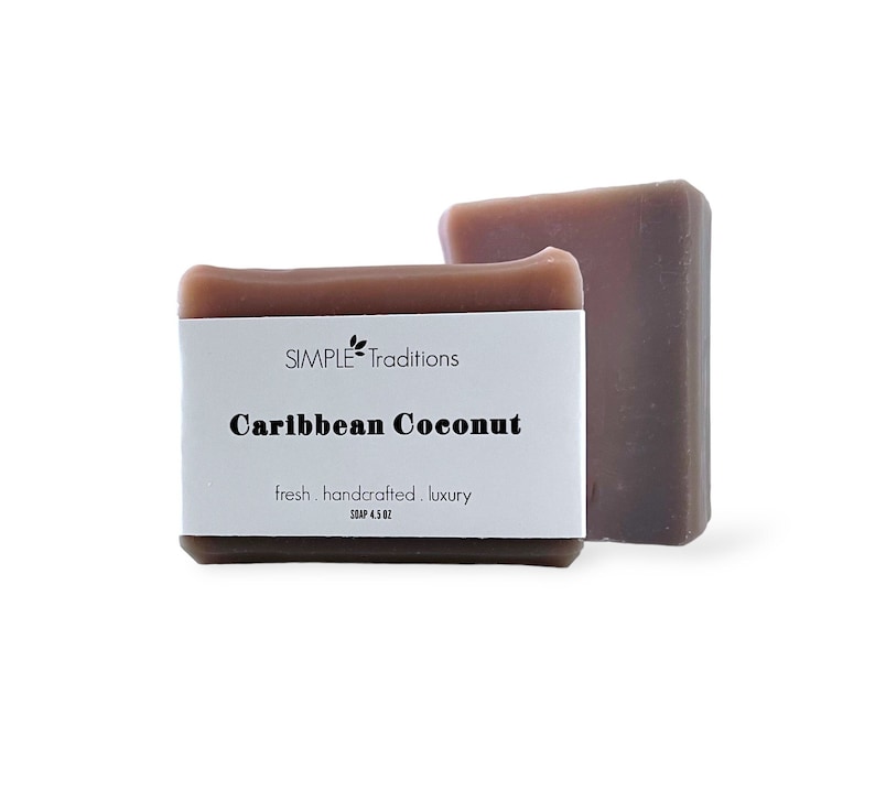 May include: Two bars of brown soap with a white label that reads "SIMPLE Traditions Caribbean Coconut fresh. handcrafted. luxury SOAP 4.5 OZ".