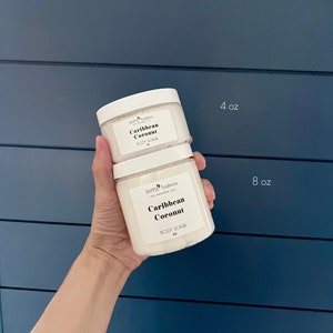 May include: Two white jars of body scrub with the text "Simple Traditions" and "Caribbean Coconut" on the labels. The smaller jar is 4 oz and the larger jar is 8 oz.
