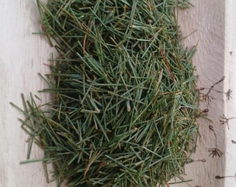 May include: A pile of dried green pine needles in a wooden bowl. The needles are a vibrant green color. The image includes a logo that says "River Valley Forager" and text that reads "Wild Foraged Plants, Herbs & Flowers for Teas, Tinctures & DIY Home Remedies."