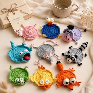 May include: A collection of eight colorful, circular crochet animal coasters featuring a pink pig, blue duck, purple donkey, teal monster, gray mouse, gray raccoon, green frog, yellow chick, and orange fox, all with stitched details.