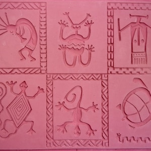 May include: Six different designs are carved into a pink rubber stamp. The designs include a stylised human figure, a lizard, a turtle, and three other abstract figures.