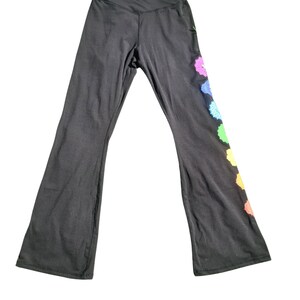 Puede incluir: Pantalones de yoga negros con un dise&ntilde;o de arco&iacute;ris en la pierna derecha. El dise&ntilde;o presenta siete formas circulares con un patr&oacute;n de tipo mandala.