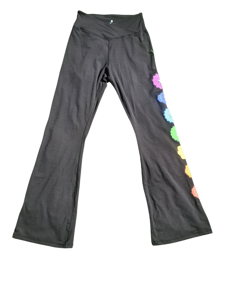 Puede incluir: Pantalones de yoga negros con un dise&ntilde;o de arco&iacute;ris en la pierna derecha. El dise&ntilde;o presenta siete formas circulares con un patr&oacute;n de tipo mandala.