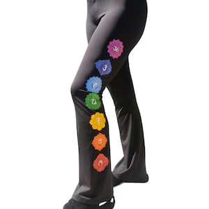 Puede incluir: Pantalones de yoga negros con un dise&ntilde;o de chakra colorido en la pierna izquierda. Los chakras est&aacute;n representados por siete c&iacute;rculos de diferentes colores con s&iacute;mbolos s&aacute;nscritos.