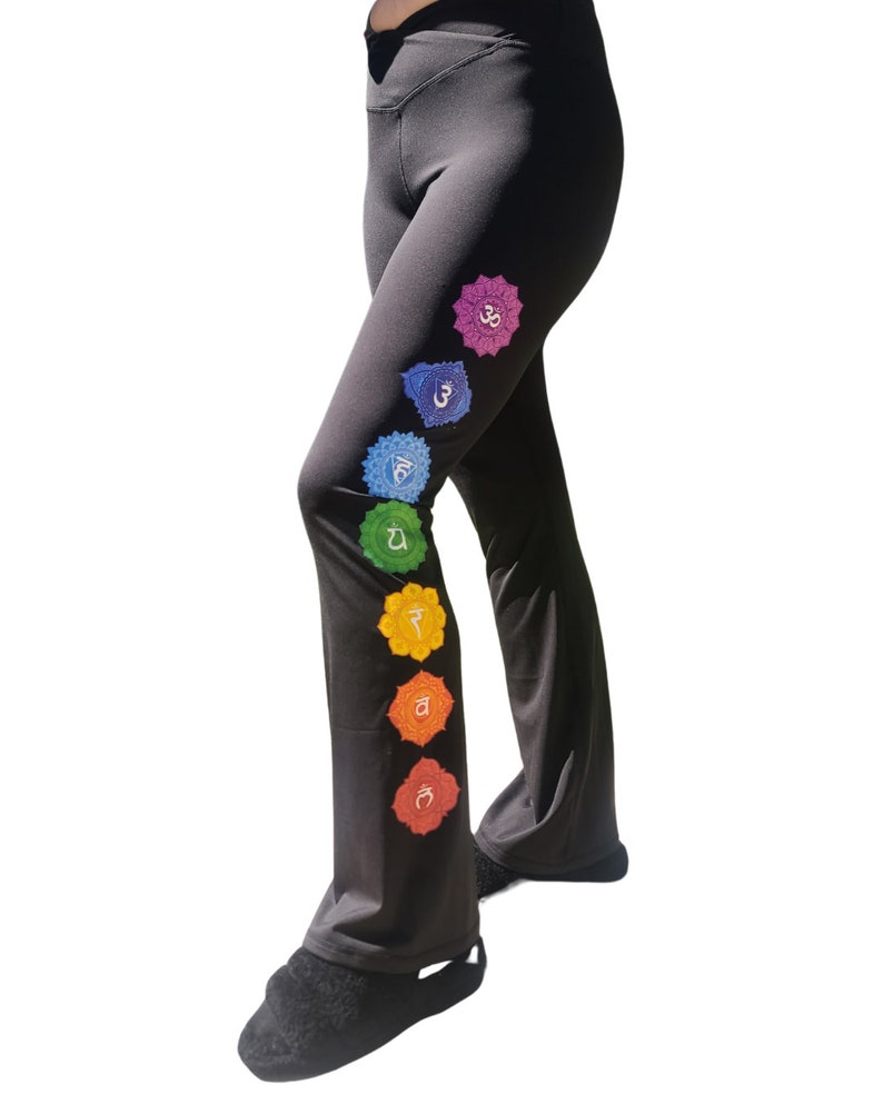 Puede incluir: Pantalones de yoga negros con un dise&ntilde;o de chakra colorido en la pierna izquierda. Los chakras est&aacute;n representados por siete c&iacute;rculos de diferentes colores con s&iacute;mbolos s&aacute;nscritos.