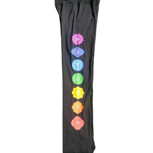 Puede incluir: Pantalones de yoga negros con un dise&ntilde;o de chakra colorido en la pierna izquierda. Los chakras est&aacute;n representados por s&iacute;mbolos y colores, incluyendo rojo, naranja, amarillo, verde, azul, &iacute;ndigo y violeta.