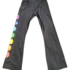 Puede incluir: Pantalones de yoga negros con un dise&ntilde;o de chakra colorido en la pierna izquierda. Los pantalones tienen cintura alta y pierna ancha.