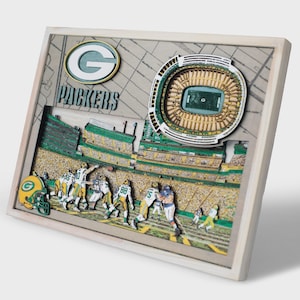 May include: A multi-layered wooden wall art piece featuring the Green Bay Packers logo, the text PACKERS, and a detailed 3D stadium model. The scene depicts a football game in progress with players on the field and a helmet in the corner.
