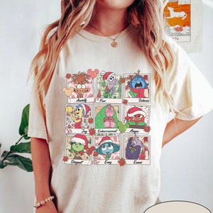 May include: Cream-colored t-shirt featuring a grid of cartoon characters representing emotions, each wearing a Santa hat. The emotions are labeled: Anxiety, Fear, Sadness, Joy, Embarrassment, Anger, Disgust, Envy, and Ennui. The word "NATURAL" is printed on the bottom.