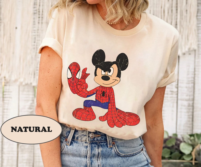 May include: A cream colored t-shirt with a cartoon image of Mickey Mouse dressed as Spiderman. The text "NATURAL" is visible in the lower left corner of the image.