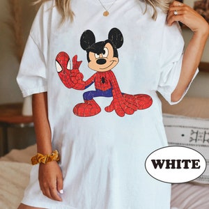 May include: White oversized t-shirt featuring a cartoon image of Mickey Mouse dressed as Spiderman. The image is in a vintage style with a distressed look. The text "WHITE" is visible in the lower right corner of the image.