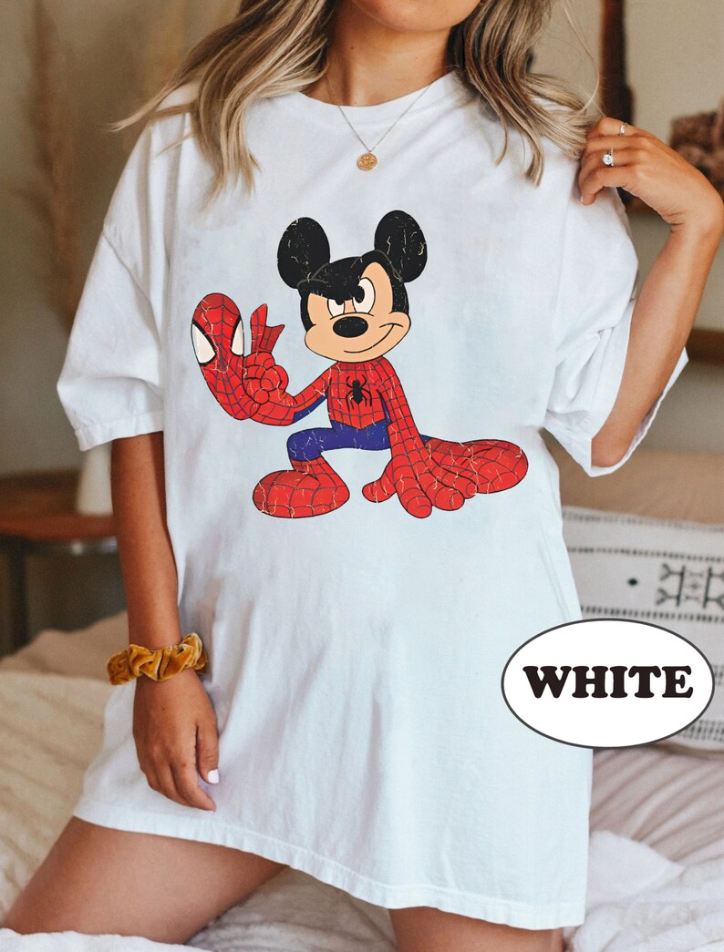 May include: White oversized t-shirt featuring a cartoon image of Mickey Mouse dressed as Spiderman. The image is in a vintage style with a distressed look. The text "WHITE" is visible in the lower right corner of the image.