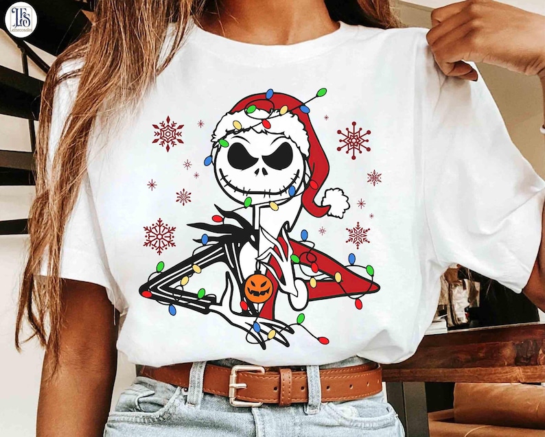 Puede incluir: Camiseta blanca con un dise&ntilde;o de Jack Skellington de The Nightmare Before Christmas, con un gorro de Pap&aacute; Noel y luces navide&ntilde;as. El dise&ntilde;o incluye copos de nieve y una calabaza. Un art&iacute;culo festivo de vacaciones.