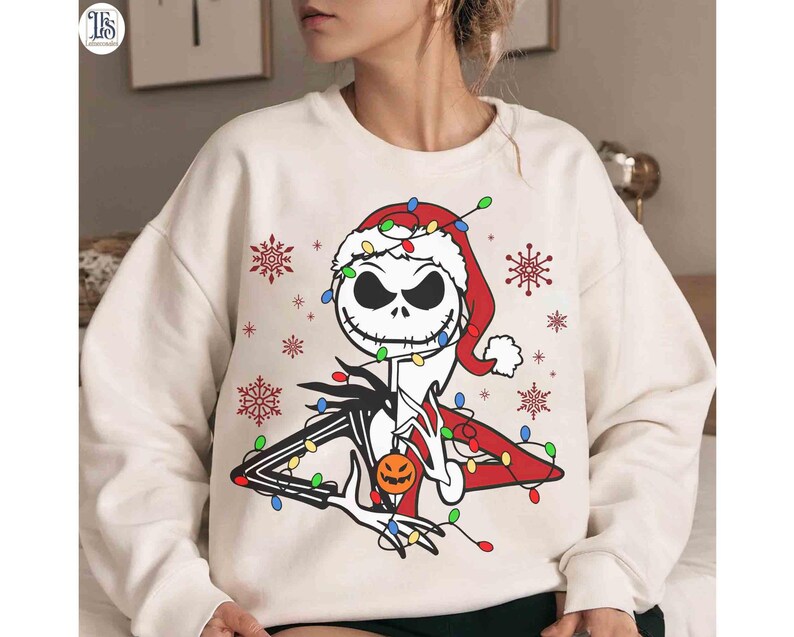 Puede incluir: Sudadera crema con un dise&ntilde;o de Jack Skellington con gorro de Pap&aacute; Noel, luces navide&ntilde;as y copos de nieve. El dise&ntilde;o incluye una calabaza, fusionando Halloween y Navidad en un estilo festivo.