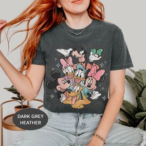 May include: Dark grey heather cropped t-shirt featuring a graphic print of Mickey Mouse, Minnie Mouse, Donald Duck, Goofy, Pluto, and Daisy Duck. The characters are arranged in a playful, overlapping design.