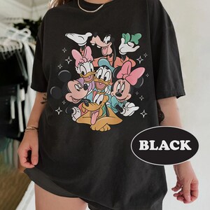 May include: Black t-shirt with a graphic print of Mickey Mouse, Minnie Mouse, Donald Duck, Goofy, and Pluto. The characters are all smiling and appear to be hugging each other. The shirt has a distressed look and is made of a soft, comfortable fabric.
