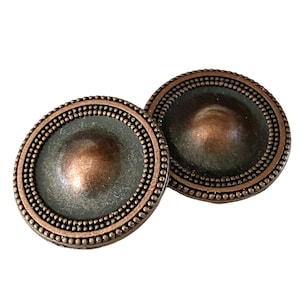 May include: Two copper-colored metal buttons with a raised, domed center and a beaded border.