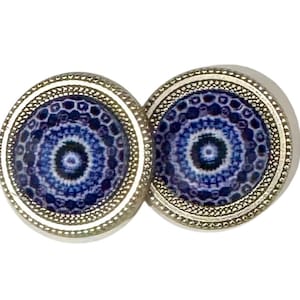 Può includere: Un paio di orecchini d'argento con disegni di mandala blu e bianchi. Gli orecchini hanno un bordo argentato con un motivo testurizzato.