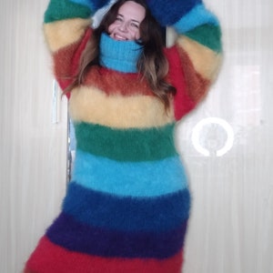 May include: A long, rainbow-striped sweater dress with a turtleneck. The dress features horizontal bands of red, orange, yellow, green, blue, and purple. The sleeves are long and the material appears to be fuzzy.