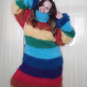 May include: A long, rainbow-striped sweater with a high turtleneck and long sleeves. The sweater features bands of red, orange, yellow, green, blue, and purple. The fluffy knitwear is a cozy and colorful garment.