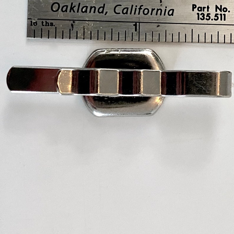 Puede incluir: Un eslab&oacute;n de pulsera de reloj de metal plateado con cinco secciones rectangulares elevadas. El eslab&oacute;n est&aacute; dise&ntilde;ado para conectarse a otros eslabones de pulsera de reloj.