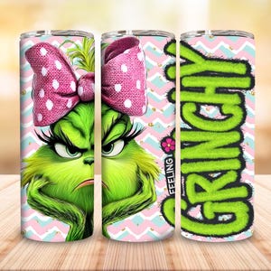 Puede incluir: Tres vasos de acero inoxidable con temática de Grinch. Los vasos presentan una cara verde del Grinch con un lazo rosa, la palabra "GRINCH" en verde y la palabra "FEELING" con una flor. El fondo tiene un patrón en zigzag rosa y azul.