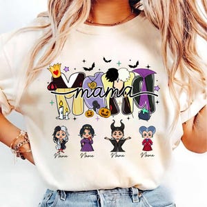 Peut inclure: T-shirt cr&egrave;me avec le mot "Mama" dans une police d&eacute;corative, repr&eacute;sentant des personnages de m&eacute;chants de dessins anim&eacute;s. Le motif comprend des chauves-souris, des &eacute;toiles, des citrouilles et un chaudron. En dessous du mot "Mama", quatre personnages de m&eacute;chants de dessins anim&eacute;s avec le mot "Name" en dessous de chacun.