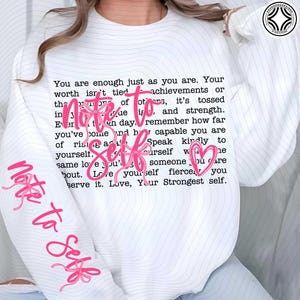 Może przedstawiać: Biała bluza z różowym napisem "Note to Self". Projekt zawiera różowe serce i inspirujący tekst. Rękawy mają napis "Note to Self" w kolorze różowym.