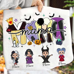 Peut inclure: Tissu blanc avec le mot "Mama" dans un design color&eacute; et stylis&eacute; avec des illustrations sur le th&egrave;me d'Halloween. Comprend des images de dessins anim&eacute;s de m&eacute;chants Disney, des chauves-souris, des &eacute;toiles et des citrouilles. Le mot "Name" est &eacute;crit sous chaque m&eacute;chant.