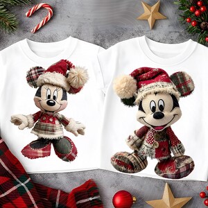 May include: Two white t-shirts featuring Mickey and Minnie Mouse plush toy designs. Both characters are dressed in Christmas attire, including red plaid outfits and Santa hats with cream-colored pom-poms. Festive holiday apparel.