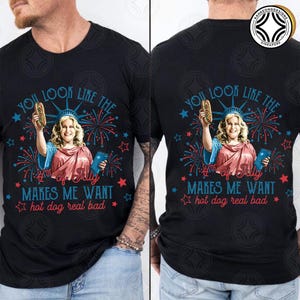 May include: Black t-shirt with a graphic of a woman dressed as the Statue of Liberty holding a hot dog. The text reads "You look like the 4th of July makes me want hot dog real bad."