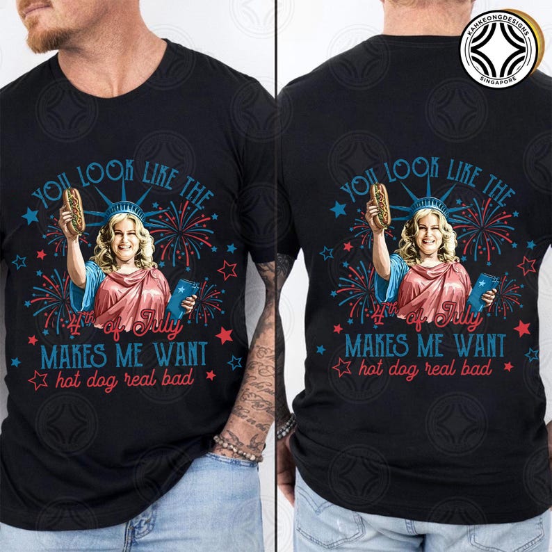 May include: Black t-shirt with a graphic of a woman dressed as the Statue of Liberty holding a hot dog. The text reads "You look like the 4th of July makes me want hot dog real bad."