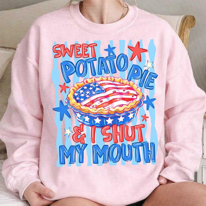 May include: Light pink sweatshirt with a graphic of a sweet potato pie decorated with an American flag design. The text reads "Sweet Potato Pie & I Shut My Mouth" in red and blue.