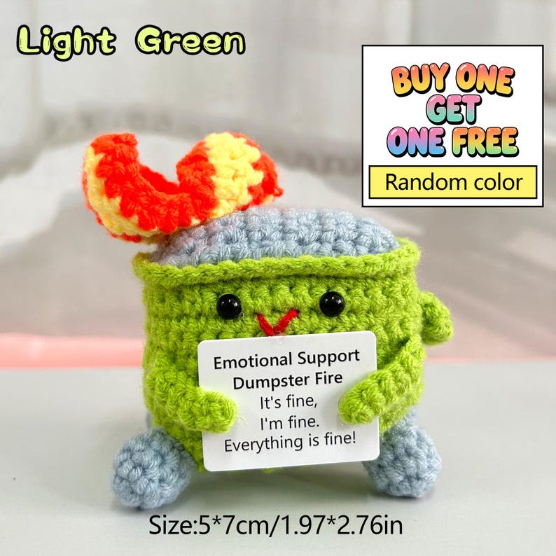 May include: A light green crocheted emotional support dumpster fire toy with a red and yellow flame. The toy has a smiling face and holds a sign that reads "Emotional Support Dumpster Fire. It's fine, I'm fine. Everything is fine!" Measures 1.97" x 2.76".