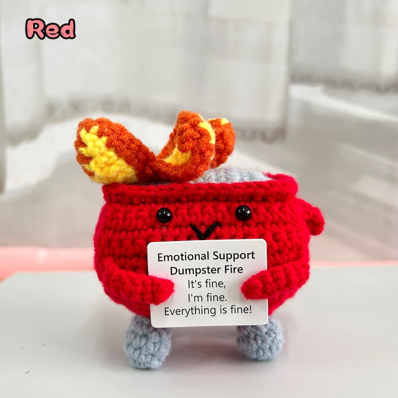 May include: Red crocheted plush toy shaped like a dumpster fire with a message that reads "Emotional Support Dumpster Fire It's fine, I'm fine. Everything is fine!"